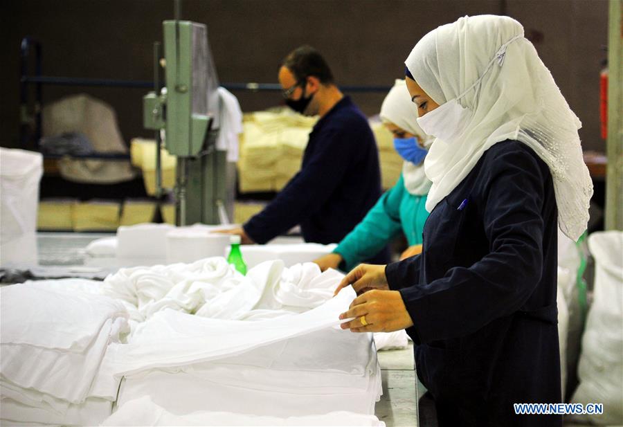 Syrian workers arrange cotton fabric for making masks in Damascus